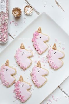 decorated cookies with pink frosting and gold decorations on a white plate next to some confetti