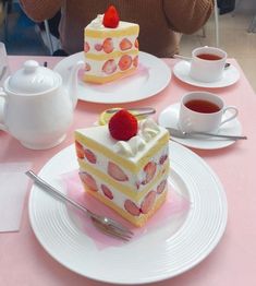 there is a piece of cake on the table with two cups and saucers next to it