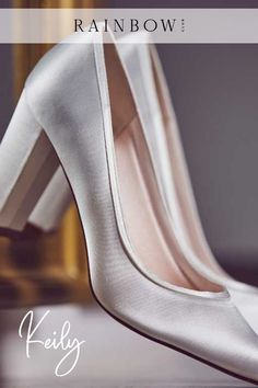 a pair of white high heels sitting on top of a table