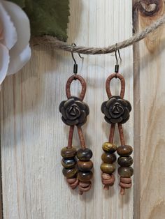 Bronze flower fashioned earrings on brown leather cord with tiger's eye colored glass dangle beads. Vintage Brown Beaded Earrings As Gift, Brown Flower Earrings With Ear Wire, Adjustable Brown Earrings For Gift, Adjustable Brown Beaded Earrings With Dangling Beads, Bohemian Brown Earrings For Spring, Brown Wooden Beads Beaded Earrings As A Gift, Brown Beaded Earrings With Wooden Beads For Gift, Gift Brown Beaded Earrings With Wooden Beads, Adjustable Bohemian Brown Beaded Earrings