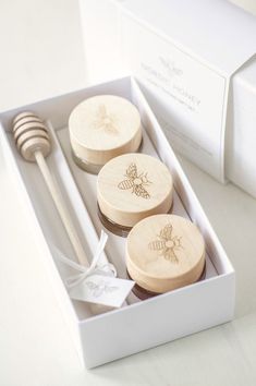 three wooden spoons in a white box next to a honey dipper and fork