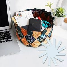 an open laptop computer sitting on top of a white desk next to a bag filled with items