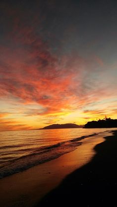 the sun is setting over the water at the beach