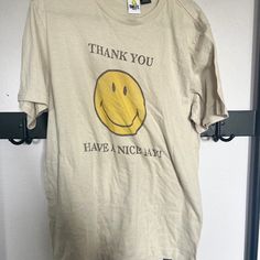 Smiley Face Tee Beige Crew Neck T-shirt With Screen Print, Cotton Short Sleeve Top With Smiley Face, Casual Smiley Face Top, Yellow Cotton T-shirt With Screen Print, Casual Tan T-shirt With Screen Print, Cotton Smiley Face T-shirt With Crew Neck, Cotton Smiley Face Crew Neck T-shirt, Casual Cotton Tops With Smiley Face, Vintage Yellow T-shirt With Text Print