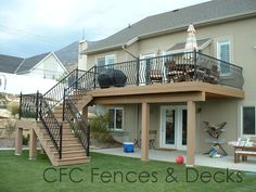 a house with a deck and stairs in the front yard, surrounded by lawn furniture