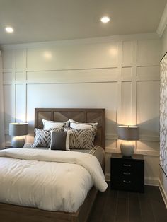 a bedroom with a bed, nightstands and two lamps on either side of the bed