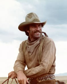 a man wearing a cowboy hat sitting on top of a horse in the middle of nowhere