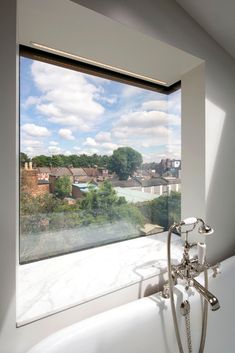 a bath tub sitting next to a window with a view of the city below it