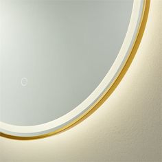 a round mirror on the wall with a gold trim around it and a white dot in the middle