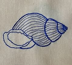 a piece of cloth with blue thread on it and an image of a seashell