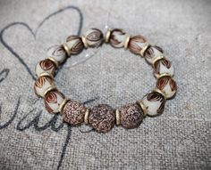 a beaded bracelet with two brown and white beads on top of a piece of fabric