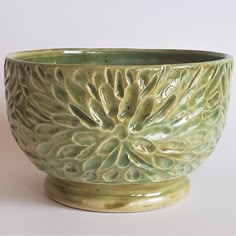 a green ceramic bowl sitting on top of a white table