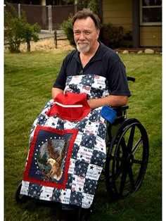 a man sitting in a wheel chair with an apron over his shoulder, holding a quilt