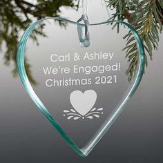 a glass ornament hanging from a tree with a heart on it's side