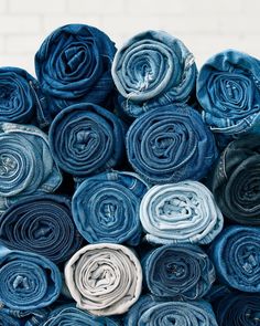 several rolled up blue jeans stacked on top of each other