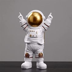 an astronaut figurine with his hands up in the air, standing on a table