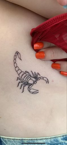 a woman's stomach with a small scorpion tattoo on her side ribcage