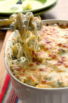 a spoon full of macaroni and cheese being lifted from a casserole dish