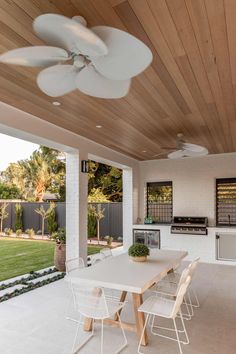 an outdoor kitchen and dining area with ceiling fans