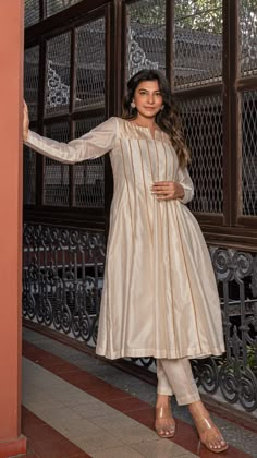 Bring on the festive spirit with our anarkali kurta set in pure tissue and chanderi silk.nPanelled Anarkali Kurta adorned with golden gota. Comes with separate inner and matching cotton silk pants.nKurta Fabric : Pure Tissue + Chanderi Silk.nPants : Cotton Silk.nDupatta : Chanderi Silk.nColour : Ivory.nModel height is 5.6” and is wearing a size S.nWash Care : Dry Clean Only.nThis product will be exclusively handcrafted for you, making the colour/texture/pattern slightly vary from the image ... Ivory Kurta Women, Cotton Silk Suit Designs Indian, Silk Churidar Designs Ideas Patterns, Tissue Suits Design Pakistani, Tissue Anarkali Dress, Tissue Cloth Dresses, Chanderi Silk Suit Designs Indian, Raw Silk Suit Designs Indian, Anarkali Suit Pattern