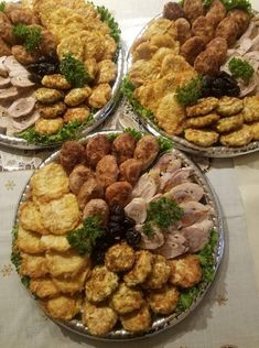 three platters filled with different types of food on top of a white table cloth