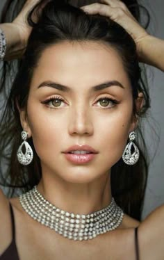 a woman wearing pearls and diamond necklaces with her hair in the middle of her head