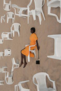 a woman in an orange dress sitting on white chairs