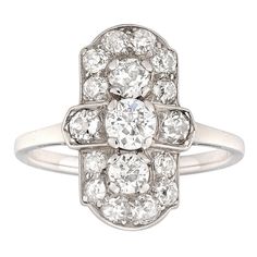 An Art Deco diamond-set plaque ring, set with seventeen old European-cut diamonds estimated to weigh 1.5 carats in total, all mounted in platinum, with D-section shank and chenier shoulders, circa 1920, head measuring 1.7x1.1cm, gross weight 3.7 grams. Finger size L This ring is in excellent condition. Unmarked, tested as platinum. A dazzling diamond-set ring made in the 1920s. This ring features a geometric plaque, emblematic of Art Deco design, set with a central diamond surrounded by sixteen Platinum Plaque, Art Deco Jewelry Rings, Yellow Gold Solitaire Ring, Leaf Engagement Ring, Gold Solitaire Ring, Art Deco Engagement, Bridesmaid Jewelry Sets, Jewellery Shop, Deco Engagement Ring