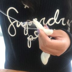 a woman is holding something in her hand and writing on the sweater that says sugared