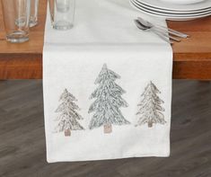 the table is set with silverware and napkins, which are decorated with pine trees