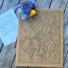 a piece of fabric with flowers on it next to an open book and pencils