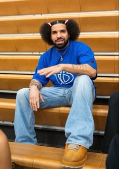 a man sitting on top of a wooden bench in front of a basketball court with his arms crossed