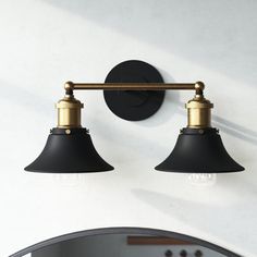 two black and gold lights are on the wall next to a mirror in a bathroom