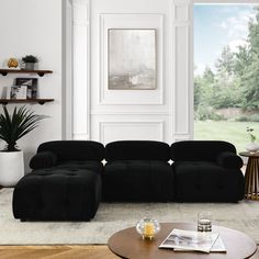 a modern living room with black couches and coffee table in front of a large window