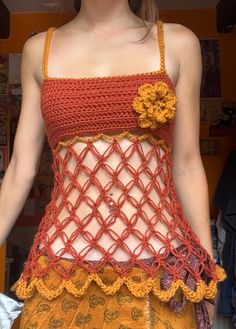 a woman is wearing an orange and yellow crochet top with flowers on it