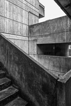 black and white photograph of stairs leading up to a concrete building with an open door