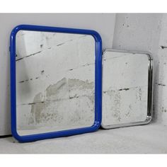 two mirrors sitting next to each other in front of a white brick wall with peeling paint on it