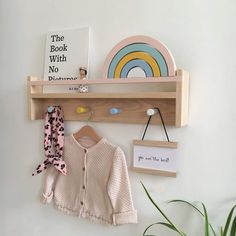 a wooden shelf with a book, hat and scarf on it next to a potted plant