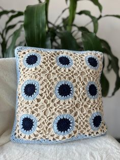 a crocheted pillow sitting on top of a couch next to a potted plant