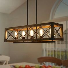 a chandelier hanging over a dining room table with fruit on the table in front of it