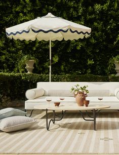 a white couch sitting on top of a wooden floor next to a table and umbrella