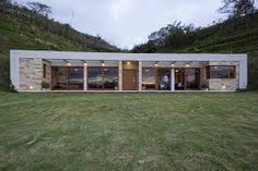 a modern house sits on top of a grassy hill