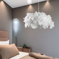 a bedroom with a large cloud hanging from the ceiling over the headboard and bed