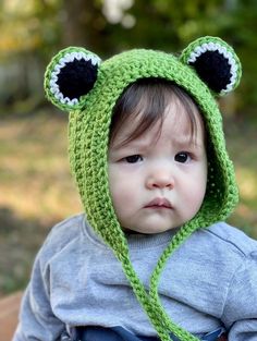 a small child wearing a green hat with ears on it's head and eyes