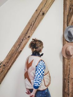 a woman standing in front of a wall with hats on it