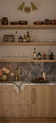 a kitchen with wooden cabinets and marble counter tops, gold faucet handles on the sink