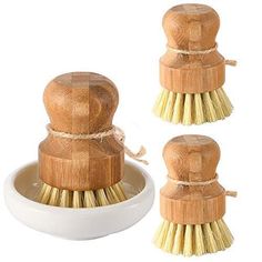 three wooden tooth brushes sitting in a white bowl on top of each other with gold bristles