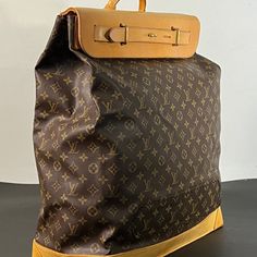 Large travel bag from the world-renowned Louis Vuitton. Crafted with meticulous attention to detail, this exquisite piece features the iconic Monogram canvas adorned with sumptuous tan cowhide leather accents, exuding sophistication and timeless elegance.  A testament to Louis Vuitton's legacy of exceptional design, this steamer bag sac showcases a near-perfect condition despite its age, reflecting the brand's commitment to quality craftsmanship. This large canvas and leather travel companion, n Luxury Backpack With Leather Handles, Luxury Coated Canvas Backpack With Leather Handles, Luxury Backpack With Leather Handles And Coated Canvas, Brown Monogram Canvas Rectangular Backpack, Brown Luxury Travel Bag, High-end Travel Backpack Shoulder Bag, Luxury Backpack For Trips, Modern Travel Bags In Signature Coated Canvas, Travel Bag With Gold-tone Hardware And Coated Canvas