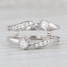 two white gold wedding rings with diamonds on each one and an engagement ring in the middle