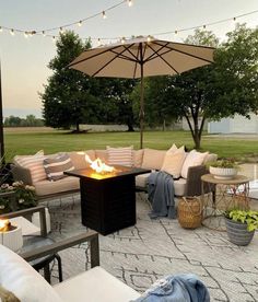 a fire pit sitting on top of a patio surrounded by furniture and an umbrella over it